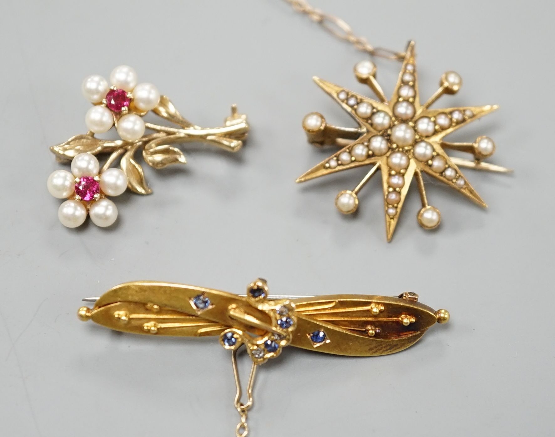 A late Victorian 15ct gold and sapphire set bar brooch, 44mm, gross weight 3.5 grams, an Edwardian yellow metal and split pearl set starburst brooch, gross weight 4.6 grams and a modern 9ct gold and gem set twin flower b